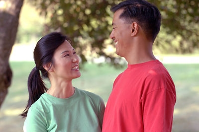 An+asian+couple+smiling+at+each+other+outdoors