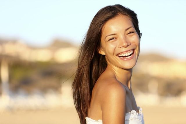 Summer woman portrait. Asian girl smiling happy laughing on beach vacation enjoying warm sunshine. Gorgeous mixed race Asian Chinese/ Caucasian female model outside.