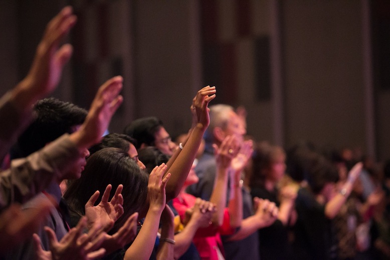 The audience lifting their hands in worship