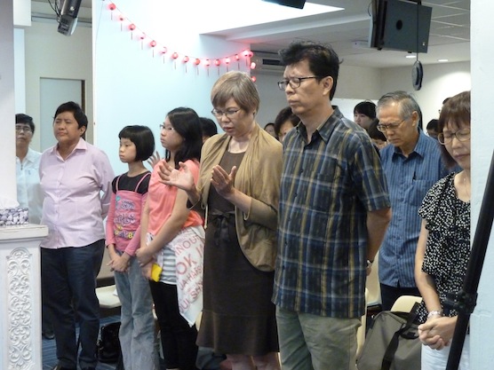 The congregation of Christian Charis Centre bowing their heads in prayer