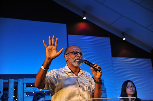 Pastor Benedict Rajan praying for the congregation