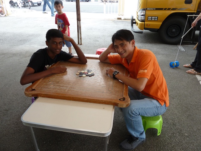 Leong Hap Choy, acting assistant director for the Rural and Urban Community Development of Malaysian CARE (right), playing with a boy 