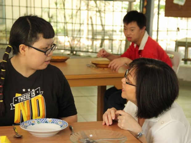 Mrs. Yammy Ang, an advisor for Wings Melaka, interacting with a young adult