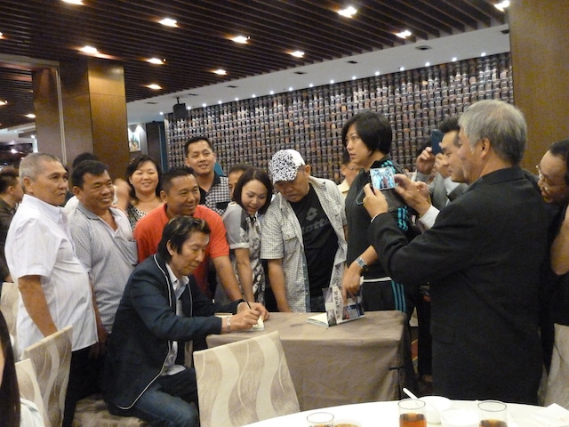 Everyone gathering around Teddy Hung to autograph his written book