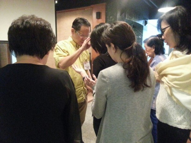 Eddy Yong praying for Jesus' mighty power of healing to come upon the people