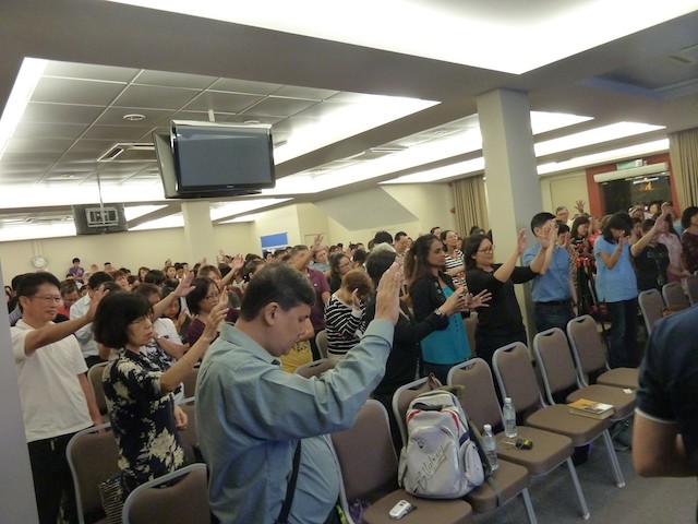 The congregation raising their hands in prayer