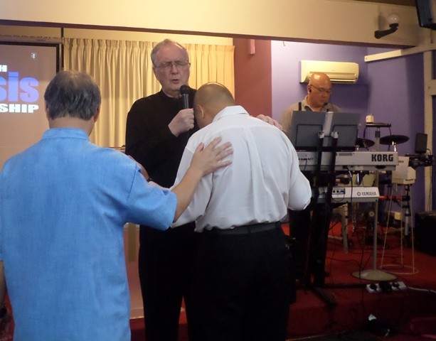 Pastor Colin praying for the church members