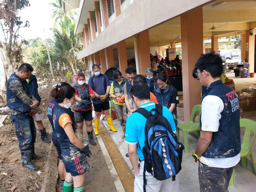 The team praying to God for strength and grace in cleaning the areas affected by the flood