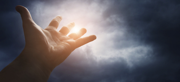 Hand reaching for the sky with dark stormy clouds