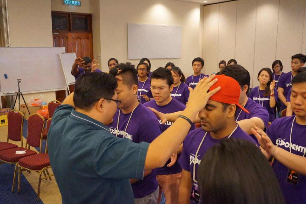 Pastor Damien Chua praying for the young adults of Exponential Camp at Taiping Golf Resort