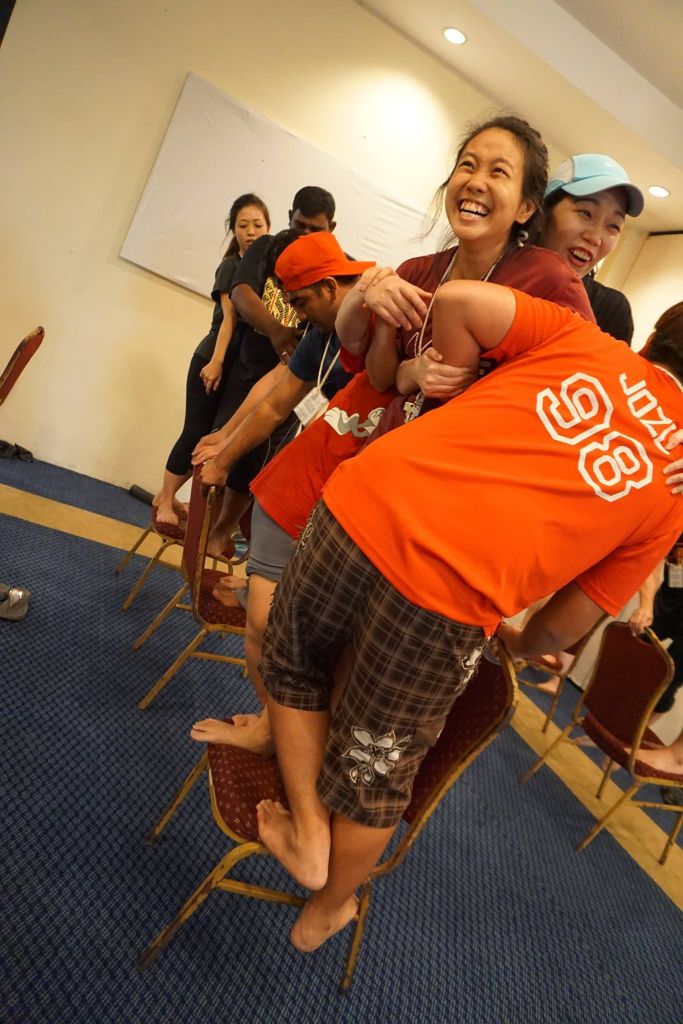 Young adults balancing on chairs, in a game session