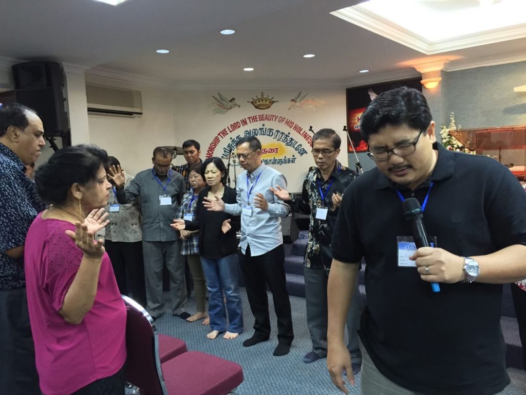 Pastor Damien Chua praying for the church pastors and leaders of PAAG