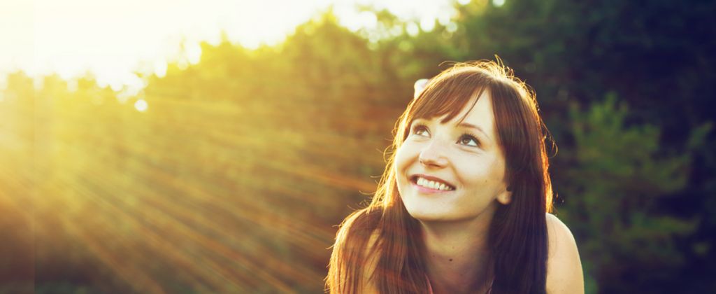 girl-smiling-on-grass-with-sun