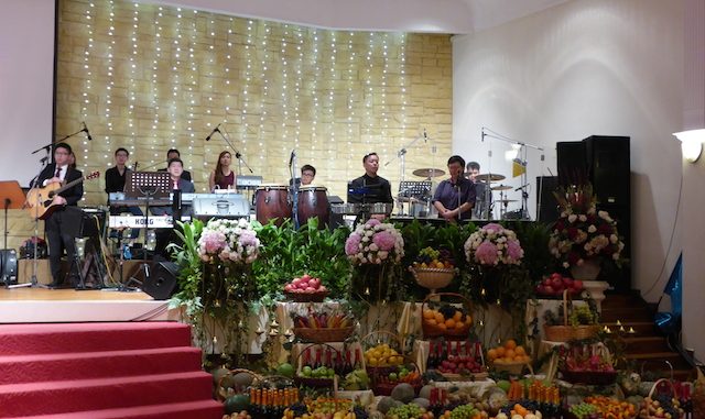 The musicians of Tabernacle of David onstage, accompanied with an array of fruits