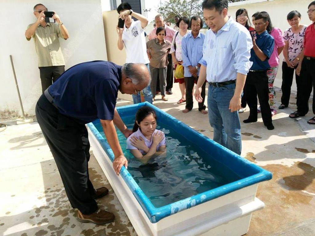 The baptism of one of the members by Elder Jacob Yeng (right) in church